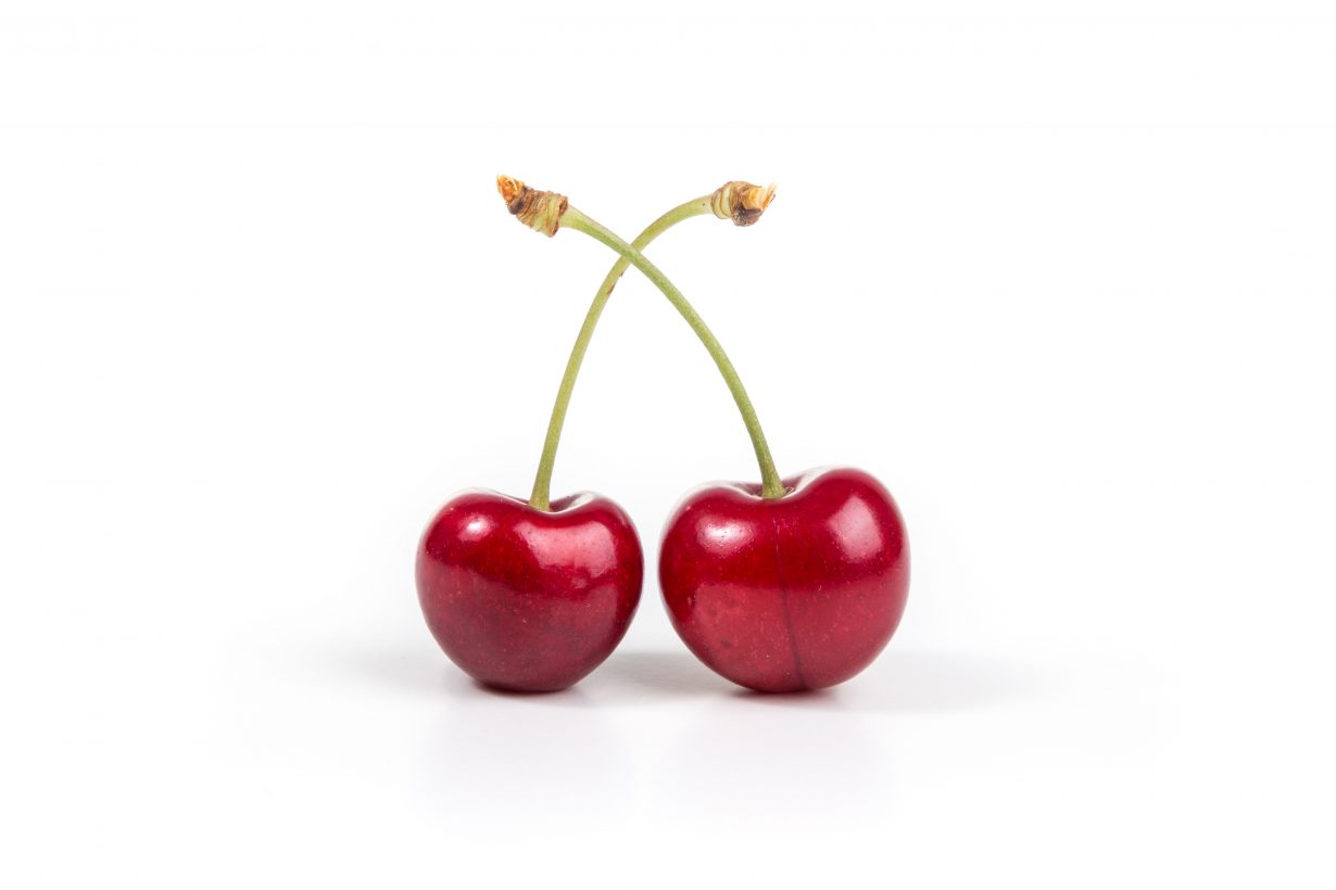 two red cherries against a white backdrop