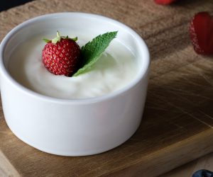 white bowl full of yogurt with a strawberry on top