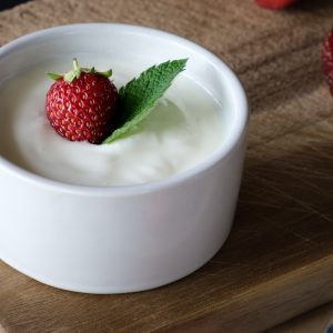 white bowl full of yogurt with a strawberry on top