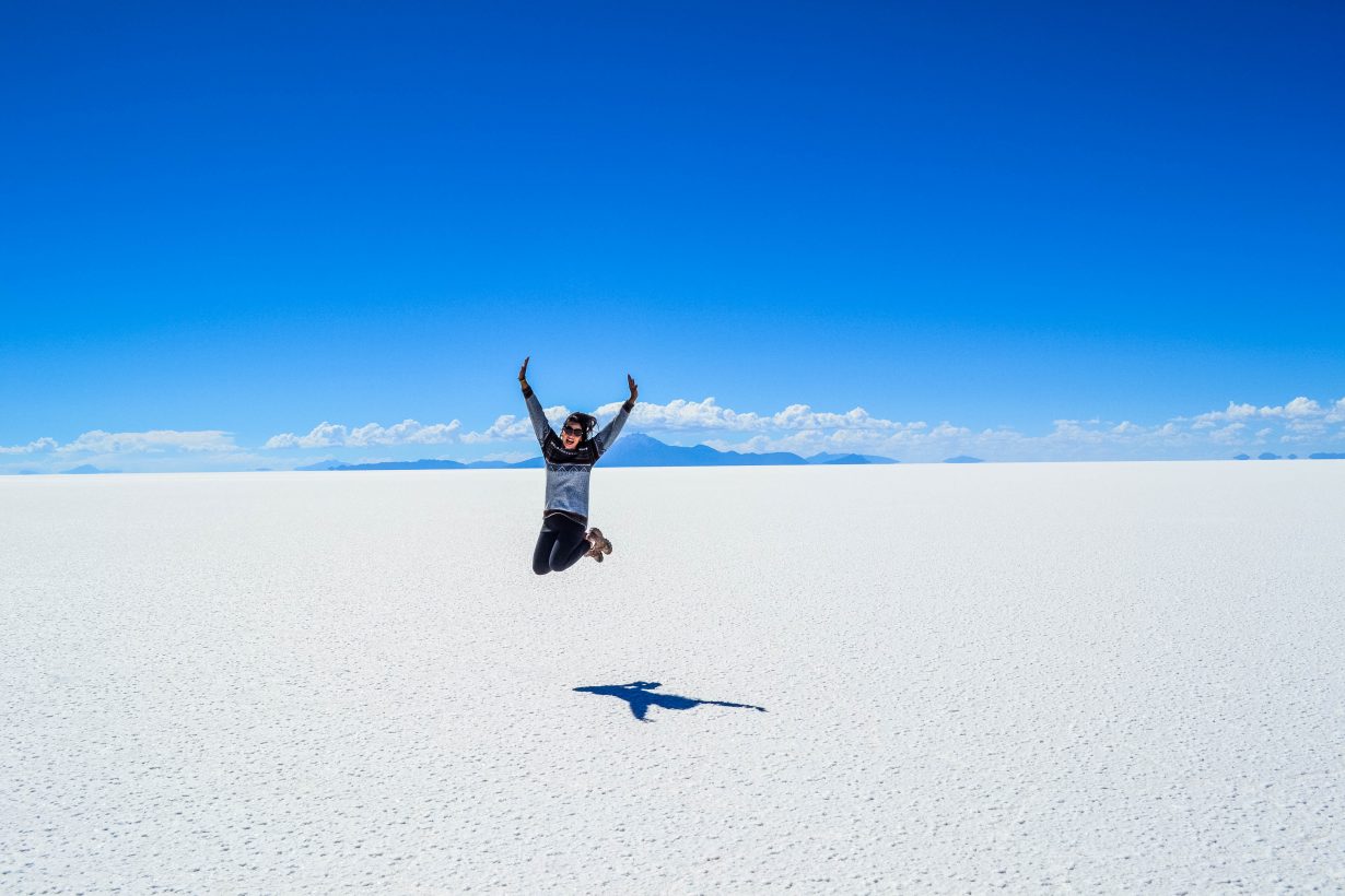 woman jumping up in the air at the salt flats