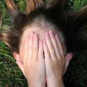 woman laying on the ground and covering her face