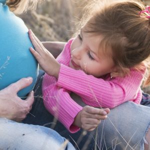 little girl touching her mother's pregnant belly