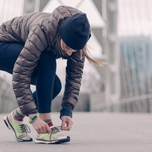 woman in workout clothes tying her shoe