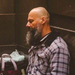 man sitting down on the floor with his head against the wall
