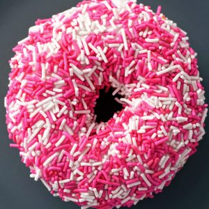 close up of a donut with pink sprinkles all over