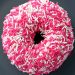 close up of a donut with pink sprinkles all over