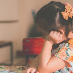 little girl sitting down and resting her head in her hand