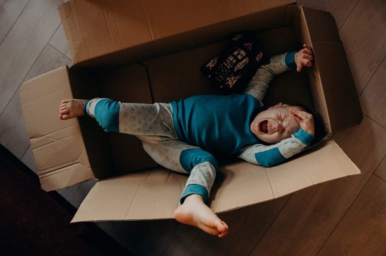 little boy crying in a cardboard box