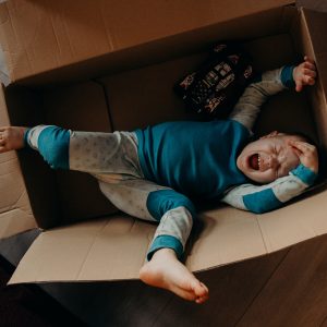 little boy crying in a cardboard box