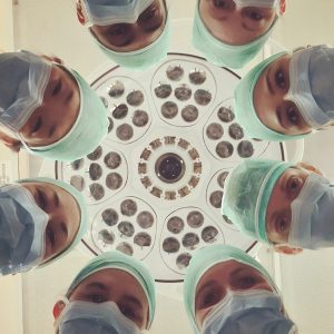 surgeons standing in a circle looking down at the camera