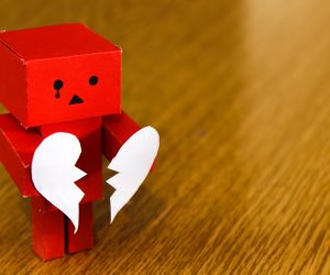 red robot holding a broken heart