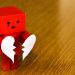 red robot holding a broken heart