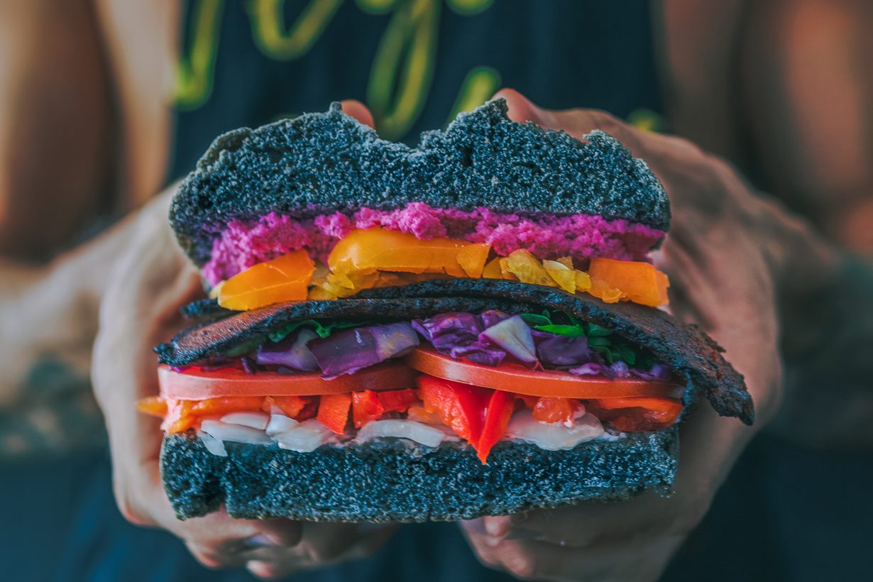 man holding a really colorful vegetable sandwich