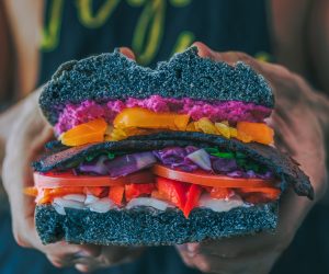 man holding a really colorful vegetable sandwich