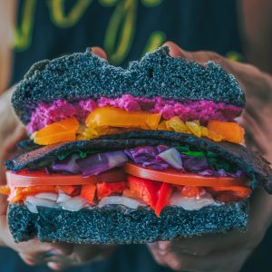man holding a really colorful vegetable sandwich