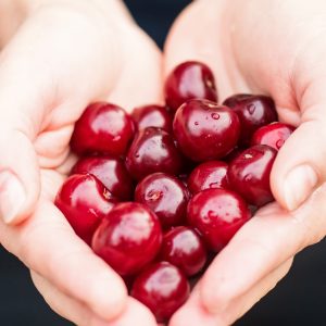 person holding cherries in their cupped hands
