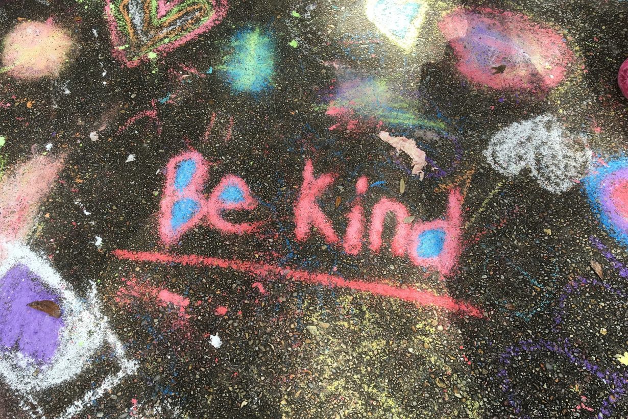 Be Kind written in sidewalk chalk on the ground