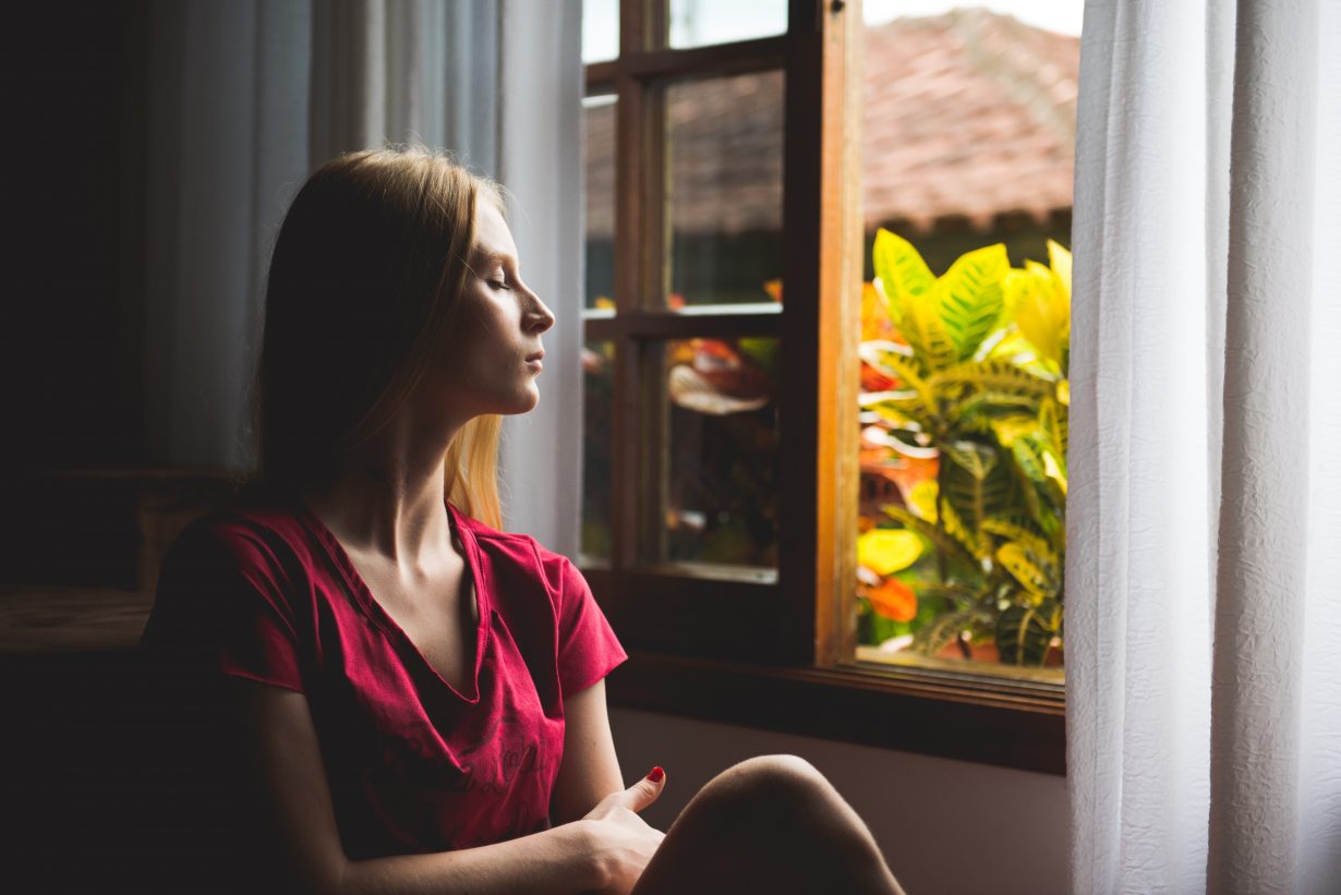 woman sitting by a window looking serene