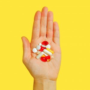 hand full of antibiotics with yellow background