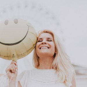 woman holding a balloon to her face and smiling