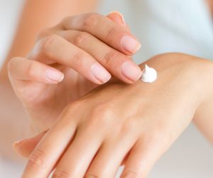 woman putting hand cream on her hands