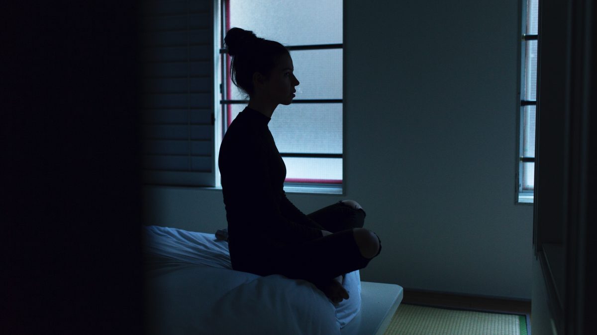 woman sitting on her bed in the dark