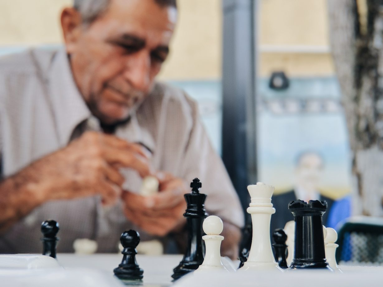 selective focus of a chess set with an older man in the background