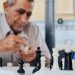 selective focus of a chess set with an older man in the background