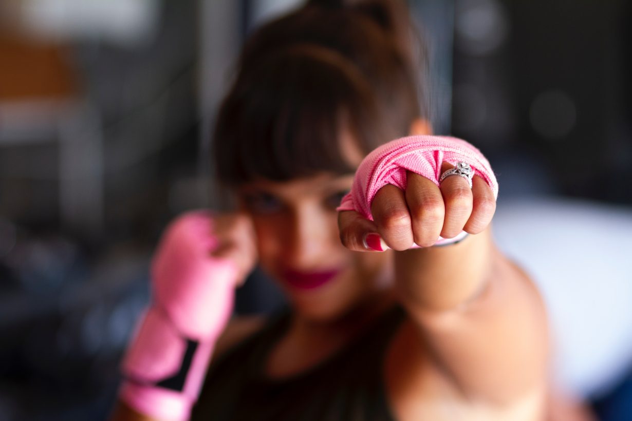 woman wearing pink boxing tape on her hands punching toward the camera