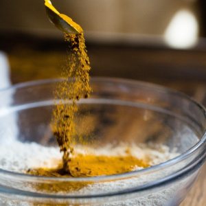 person pouring powdered turmeric into a bowl