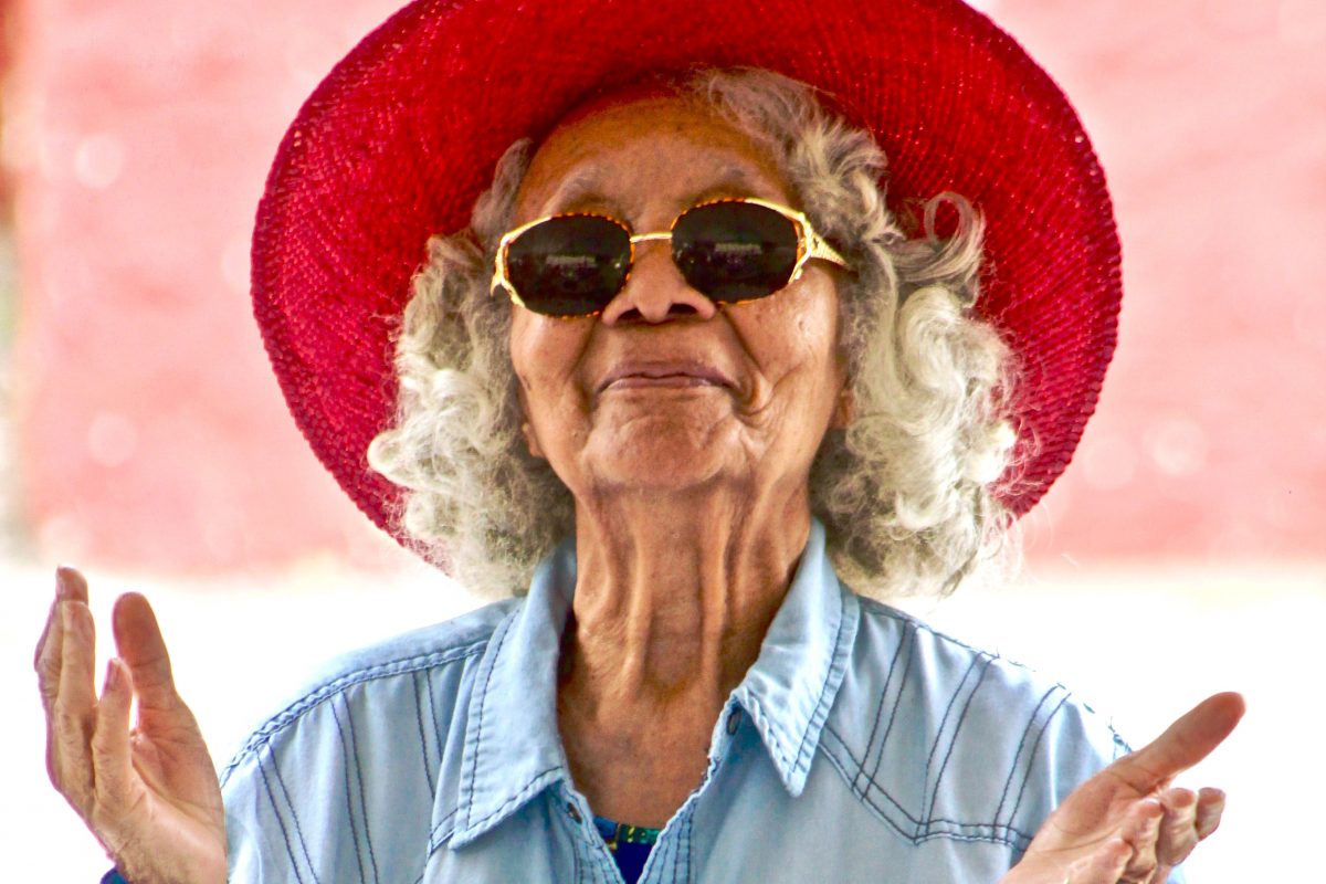 older woman smiling wearing a red hat