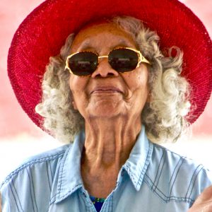older woman smiling wearing a red hat