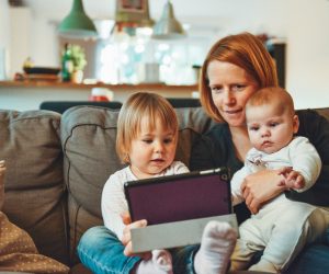 woman sitting with her two kids looking at a tablet