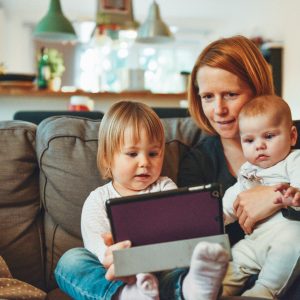 woman sitting with her two kids looking at a tablet
