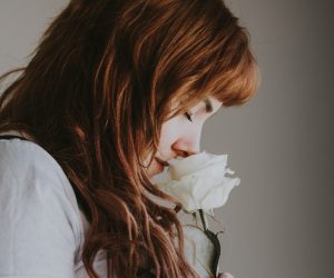 woman sniffing white flower