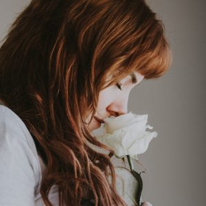 woman sniffing white flower
