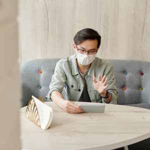 man wearing face mask and talking on a tablet