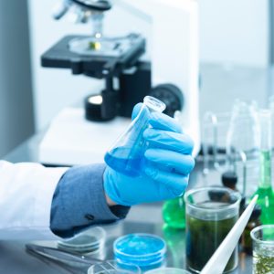 person working in a science lab with test tubes and beakers