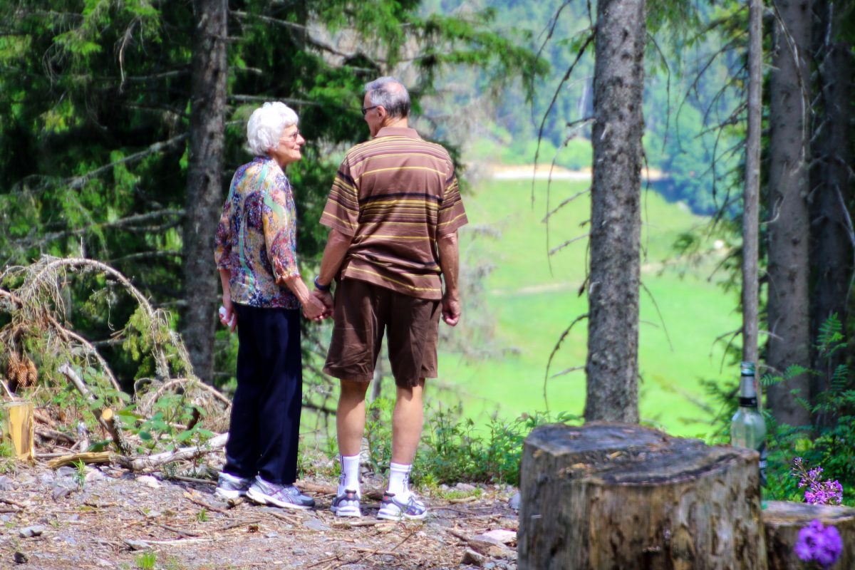 old woman and man holding hands in a forest