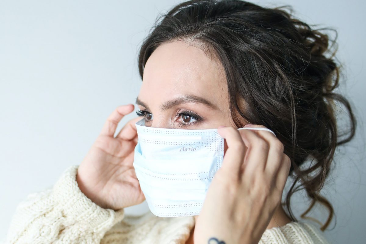 woman putting on surgical mask