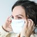 woman putting on surgical mask
