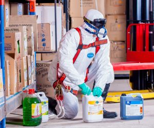 man in white suit working with chemicals