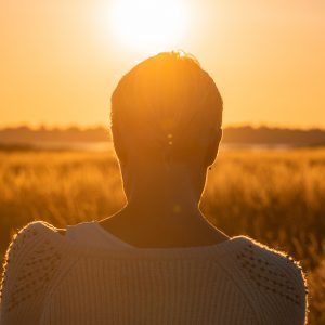 woman facing the sunset in a field