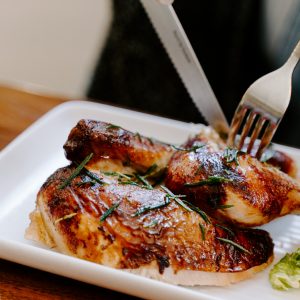 person cutting into some chicken