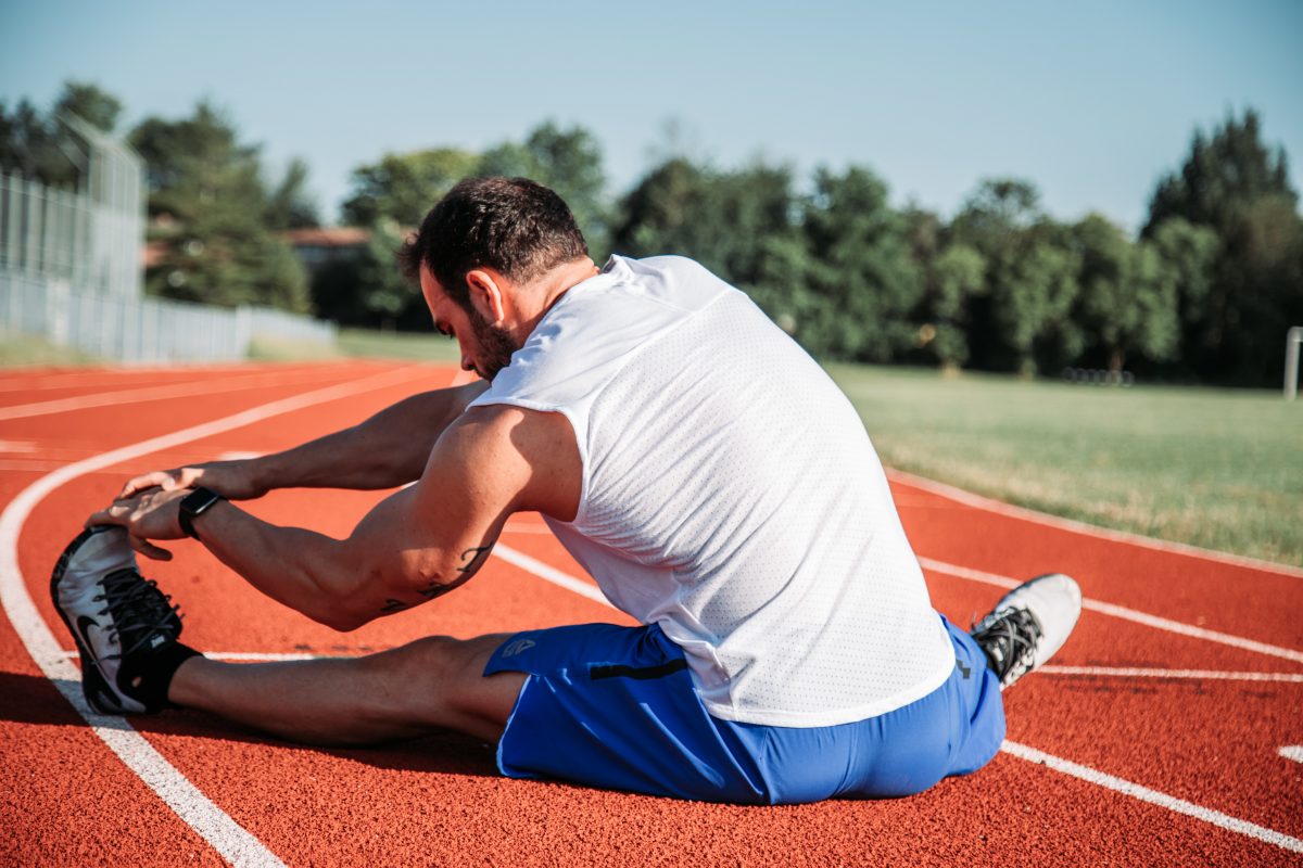 man stretching on a runners track