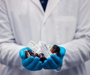 person in a lab coat holding medicine vials