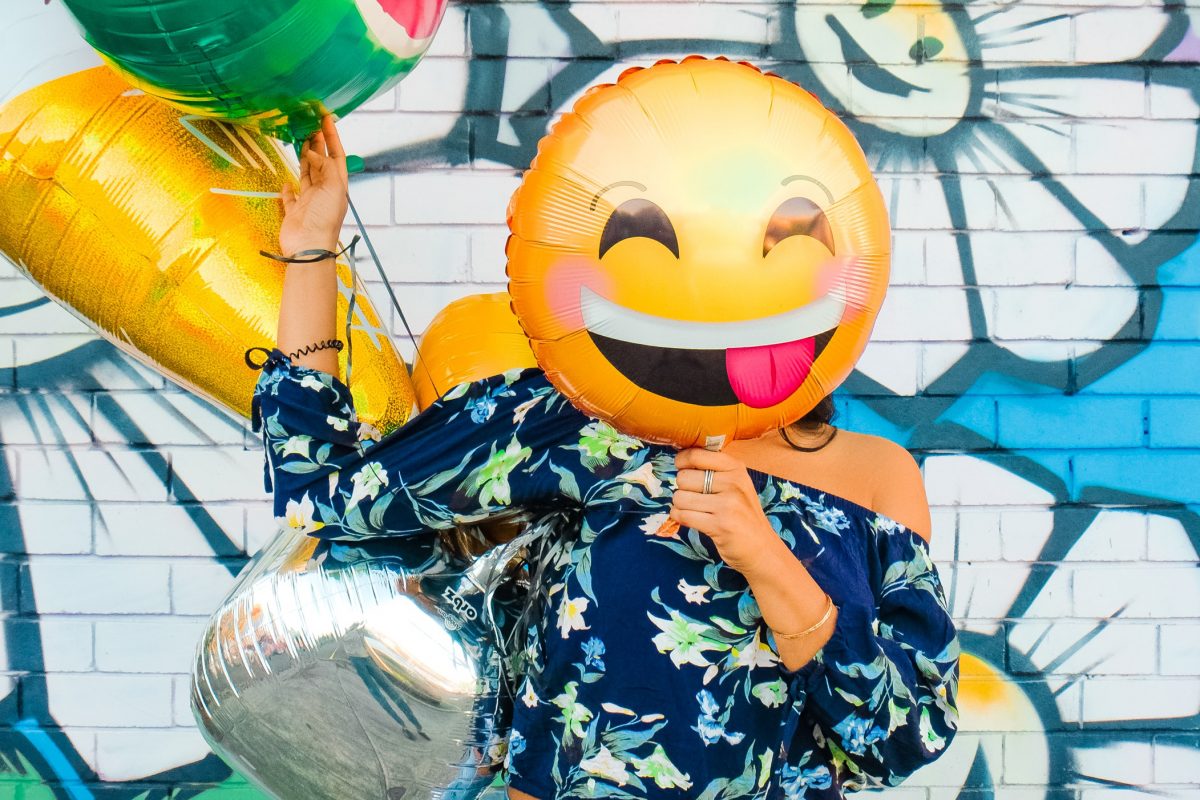 person holding a smiley face balloon