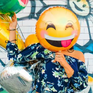 person holding a smiley face balloon
