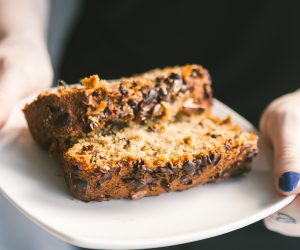 woman holding plate with banana bread slices on it