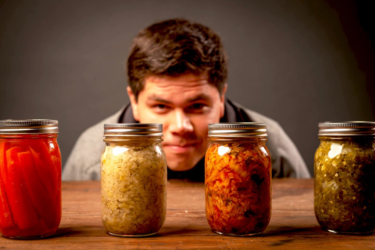 man looking at jars of fermented vegetables